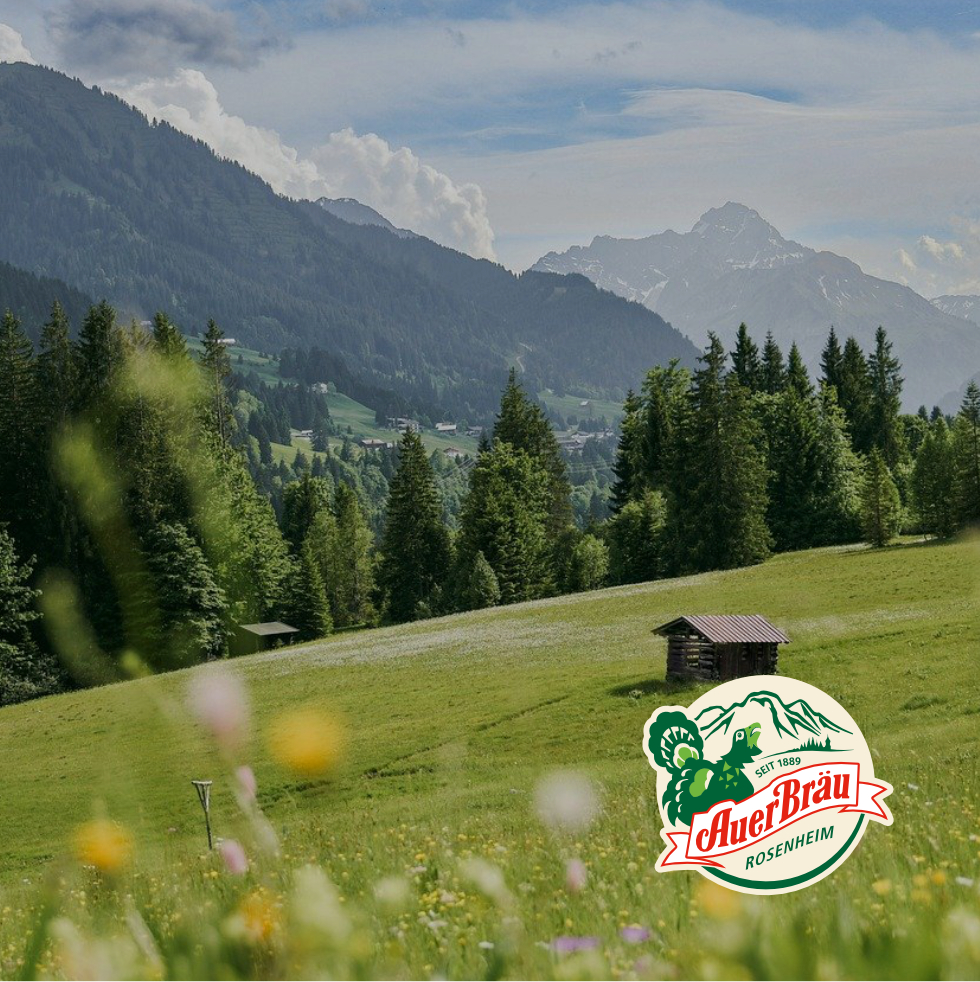Aufnahme einer Berglandschaft, im Vordergrund liegt das Logo der Brauerei Auerbräu.